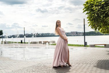 Genç kadın yaz tatilinde yalnız poz veriyor göl kenarında şirin bir elbise içinde, yaşam tarzıyla