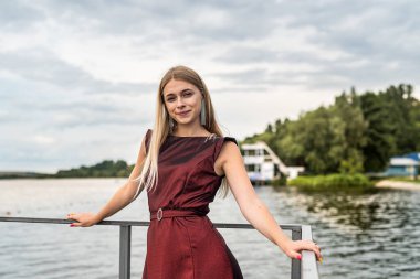 Güzel bir kadın doğada uzun koyu kırmızı bir elbise giyiyor. Seyahat kavramı.