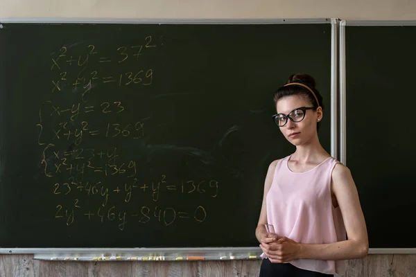 Młoda Poważna Nauczycielka Wyjaśnia Formuły Matematyczne Uniwersytecie Obok Tablicy — Zdjęcie stockowe