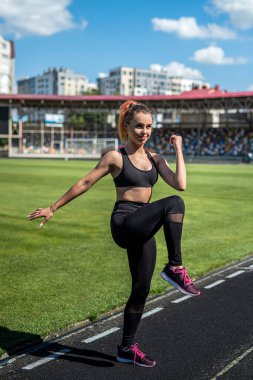 Genç sporcu bayan sporcu. Stadyumda bacaklarını açıyor. Sağlıklı bir yaşam tarzı.  