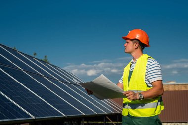 Güneş enerjisi santralinde çalışan üniformalı bir mühendis. Güneş istasyonu geliştirme kavramı