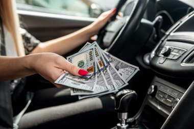 Kadın eli bize bir arabada dolar sayıyor, satın alma veya kiralama konsepti