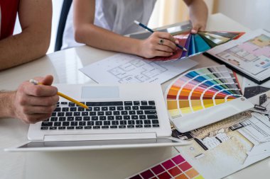 Tasarımcılar yeni projeyi tartışıyor ve dizüstü bilgisayarda notlar alıyor