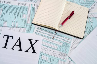 Amerikan vergi formları yanında kalemle birlikte bir defter olan bir masanın üzerine konur.