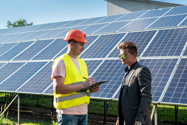 Двое мужчин планируют установку солнечных панелей. Командная работа в бизнесе