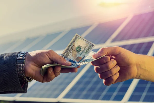 Male handshakes close up against solar panels .