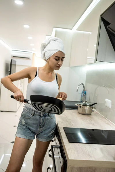 Ev hanımı elinde kızartma tavasıyla duştan sonra kahvaltıya hazırlanıyor.