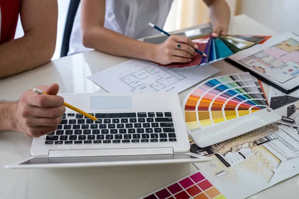 Tasarımcılar yeni projeyi tartışıyor ve dizüstü bilgisayarda notlar alıyor