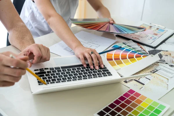 Tasarımcılar yeni projeyi tartışıyor ve dizüstü bilgisayarda notlar alıyor