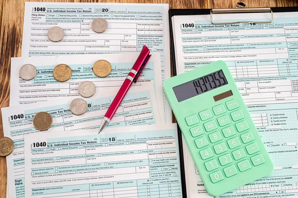 Masanın üzerinde düzgünce katlanmış Amerikan formları var. Üzerinde madeni paralar, kalem, hesap makinesi.