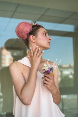 Genç ve çekici bir kadın. Yüzüne yakın ellerle poz veriyor.