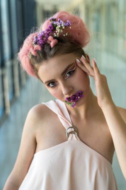 Koridorda yerde oturmuş kameraya poz veren genç bir kadın.