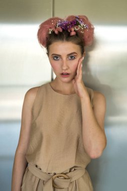 Bej elbiseli, profesyonel makyajlı ve kameraya poz veren genç ve güzel bir bayan.