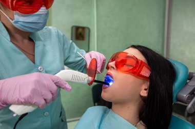 Diş hekimliğinde ultraviyole lambalı diş hekimi hastayı beyazlatıyor.