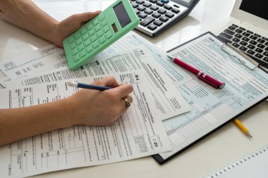 ABD vergi formunu bilgisayarı ve hesap makinesiyle dolduran bir kadın. Bireysel gelir vergisi beyanı