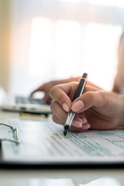 Kadın eli vergi formunu dolduruyor, 1040. Vergilendirme kavramı.