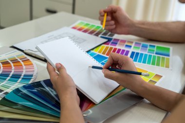 Yaratıcı tasarımcılar dizüstü bilgisayardaki yeni proje hakkında notlar alıyorlar