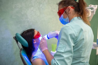 Kadın bir hastayla beyazlatma prosedürüne hazırlanan dişçi.