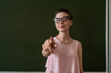 Güzel öğretmen boş okul tahtasının yanında yeni bir ders açıkladı, metin için kopyalama alanı