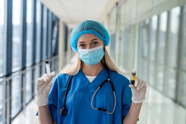 young quality nurse in uniform with a stethoscope around his neck holding a syringe in front of the patient's ward. Medicine concept
