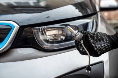 Tamirci, farında kablolar olan modern H7 ampulü kuruyor.