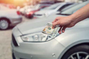 Kiralık ya da araba almak için dolar tutan adam. başarı anlaşması konsepti
