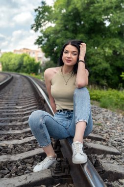 Esmer genç bir kadın tren raylarında duruyor, yaz gezisinde.