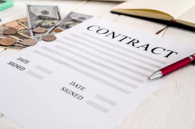 Kalem ve dolarlarla yapılan sözleşme ahşap bir masanın üzerinde. İş konsepti
