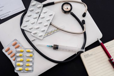 on closed white laptop tablet syringe stethoscope thermometer standing on black background. Medicine concept
