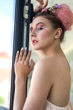 Genç ve çekici bir kadın. Yüzüne yakın ellerle poz veriyor.