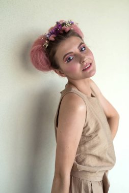 Bej elbiseli, profesyonel makyajlı ve kameraya poz veren genç ve güzel bir bayan.