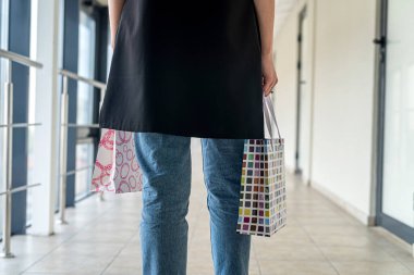 Alışveriş merkezinin içinde alışveriş torbaları olan genç bir kadın. Kara Cuma. Satış ve indirimler 