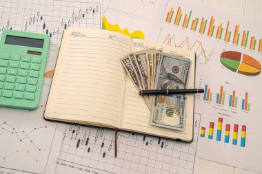 Projelerin iş çizelgeleri arasında bir hesap makinesi, dolar banknotları ve bir kalem var. İş konsepti