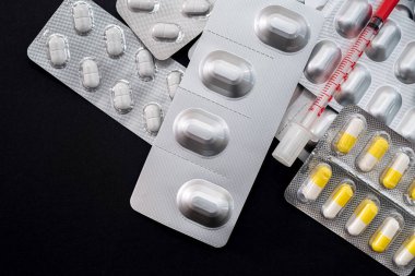 Siyah arka planda bir şırıngayla hazırlanmış bir sürü ilaç var. Tıp konsepti