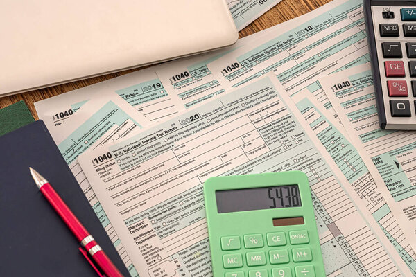 new tax forms 1040 two calculators pen notebook and notebook lie on a wooden table. The concept of documents