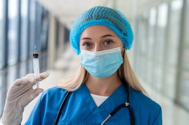 Eldivenleri steteskoplu ve maskeli iyi bir hemşire şırınga tutuyor. Tıp konsepti