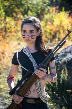 Kadın avcı tepede. Doğada, dışarıda silah ya da tüfek kullanıyor.