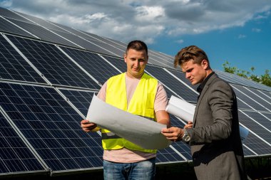 Güneş panellerinin yanında çalışan patrona çalışma planını gösterir.