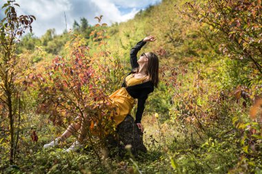 Sonbahar yapraklarına yakın genç bir kadının portresi parkta ılık bir ışıkta.