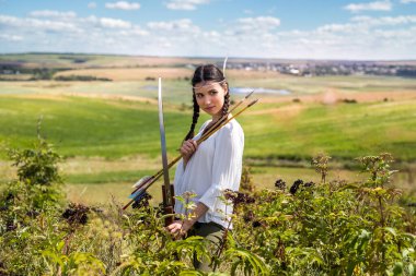 Yaylı güzel bir dişi avcı, açık havada yerli Amerikan yerlisi rolü oynuyor.