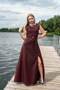 Gölde poz veren koyu kırmızı elbiseli güzel sarışın kız, romantik.