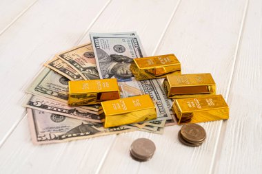 Dolar sikkeleri, parlak altın külçeler, yeni ahşap bir masanın üzerinde yatıyor. İş konsepti