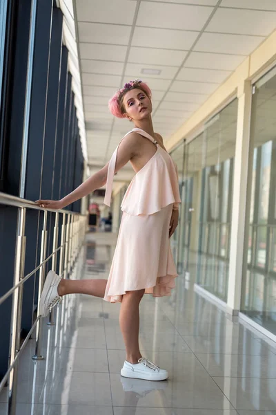 Pembe elbiseli, çiçekli genç bir kadının tam boy fotoğrafı.