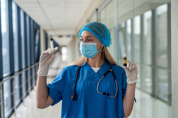 young quality nurse in uniform with a stethoscope around his neck holding a syringe in front of the patient's ward. Medicine concept