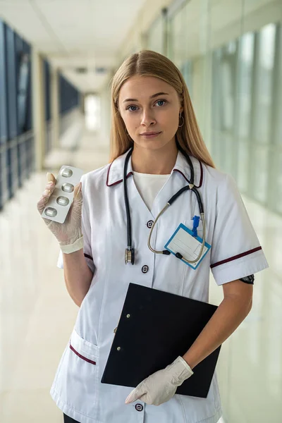 young beautiful nurse stands in the hallway with a stethoscope and a tablet. Medicine concept