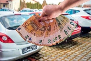 Manikürlü güzel genç kadın elleri arabaların arka planında büyük miktarda euro banknotları tutuyor. Alışveriş konsepti. İş konsepti
