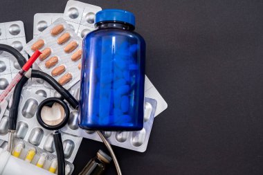 Birçok tıbbi ilaç steteskop hapları siyah arka plana şırınga düşürür. Tıp konsepti