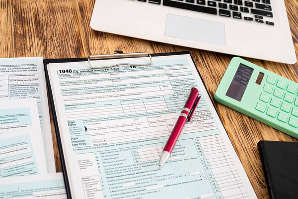 useful notebooks with red pen and tax forms 1040 usa scattered on a wooden table. Documentation concept