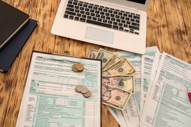 Beyaz defter vergisi formu US 1040 dolar banknotlar ve paralar tahtadan bir masanın üzerine serilmiş. İş konsepti