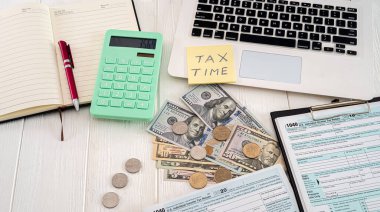 Beyaz defter yeşil hesap makinesi kalem vergisi formu 1040 dolar ve bozuk paralarla dolu paralar geniş bir masanın üzerinde. Belgelendirme ve iş konsepti